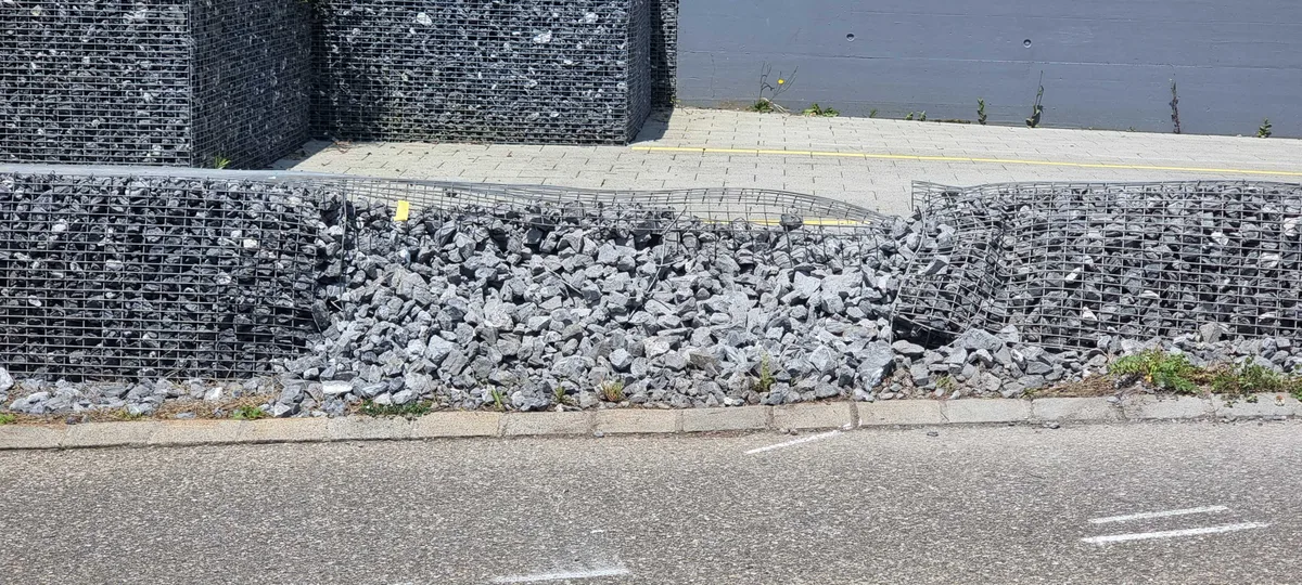 An dieser Stelle dürfte der Unfallwagen ein erstes Mal in die niedrige Schottersteinmauer geprallt sein. Man sieht einen Schaden an einer Schottersteinbegrenzung.